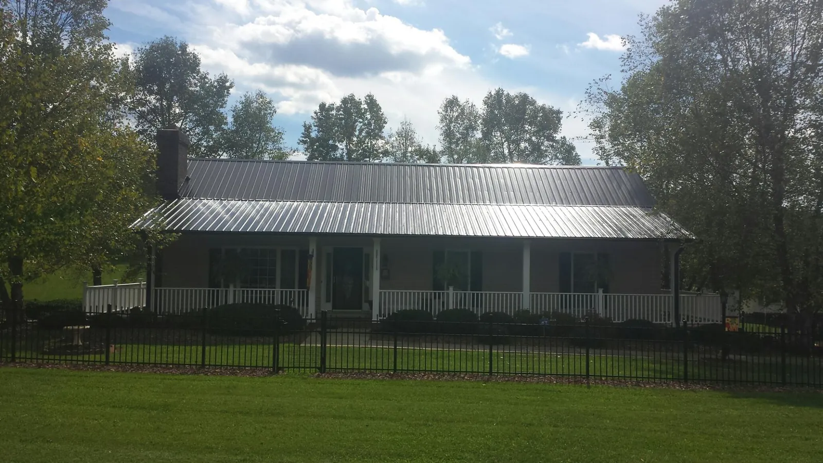 Gray metal roof on a brick ranch with a full width front porch — Gutter Guard Installation work by our crew in Beaver Dam
